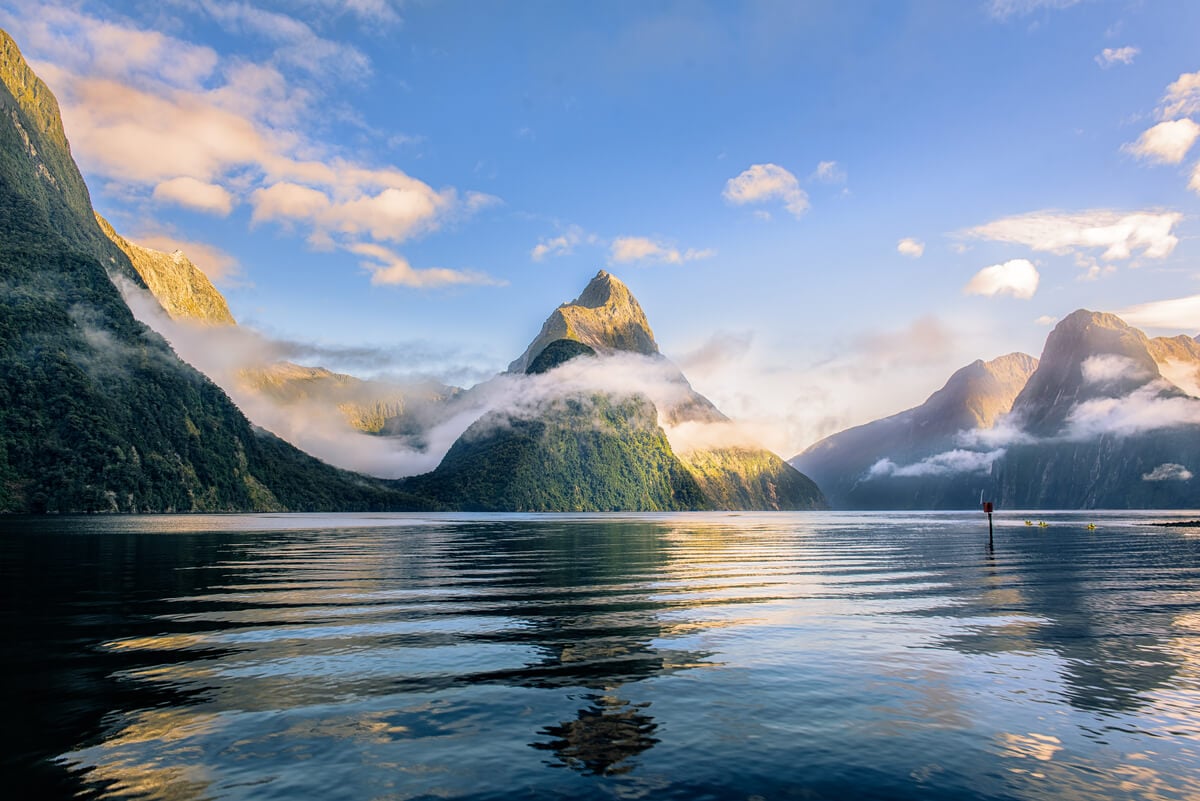 Misty mountains over still black water at Milford Sound, Fiordlands - top destination in New Zealand