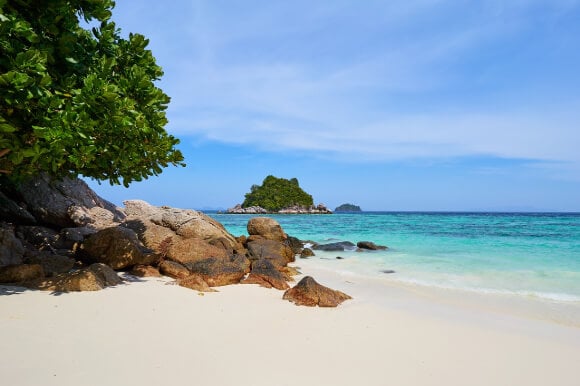 a view of a white sand beach with turquoise blue water in Koh-Lipe