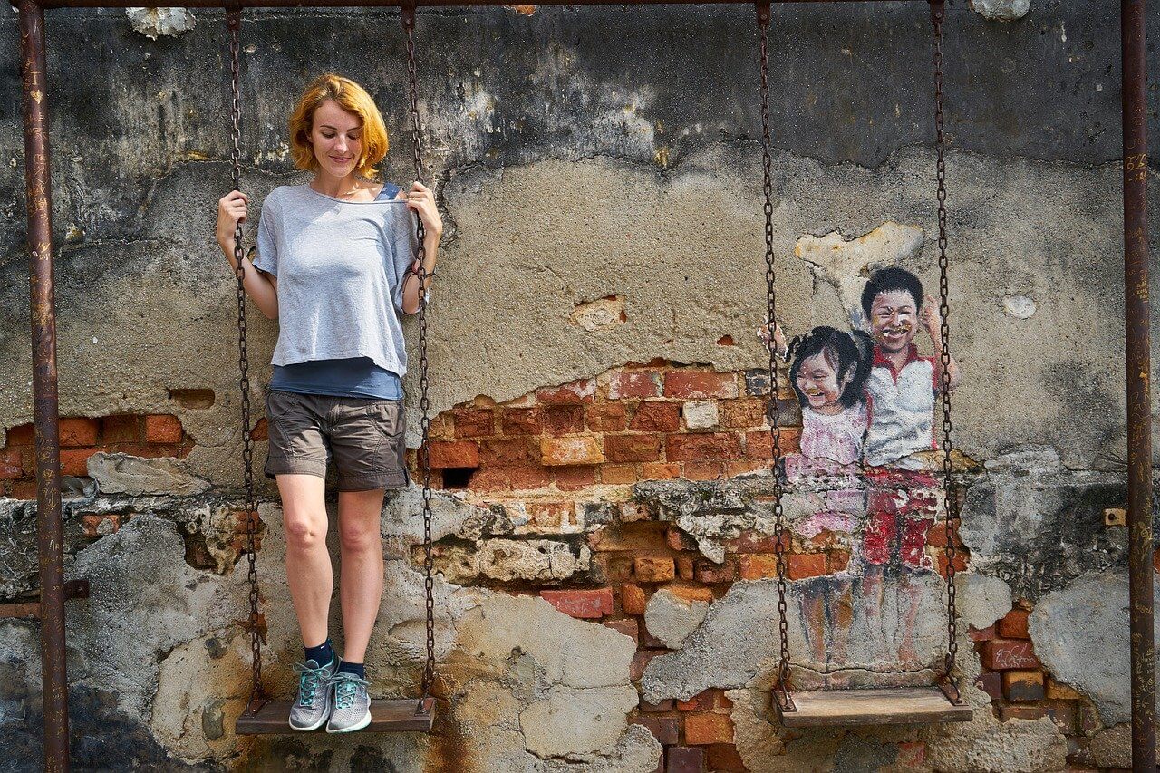 A tourist on a swing next to cool street art in Malaysia