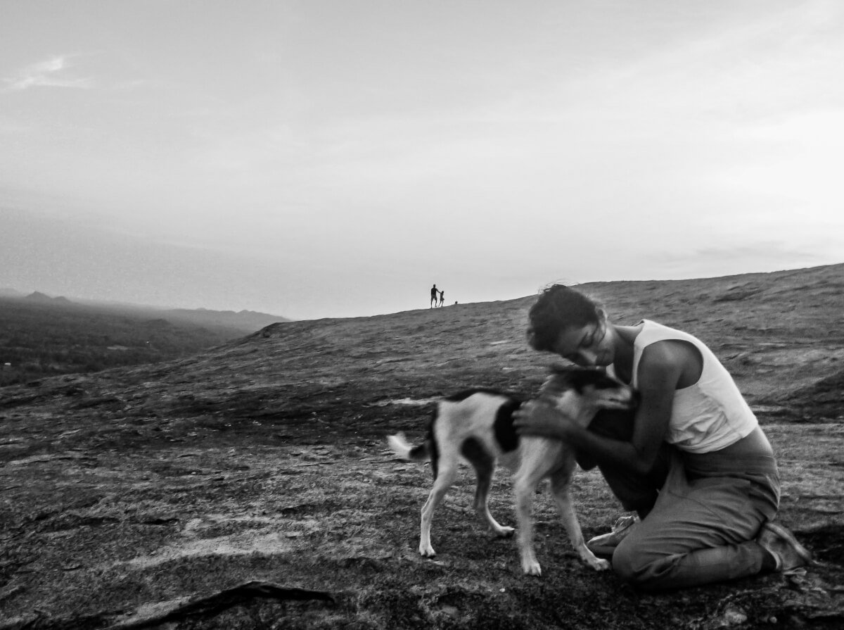 A kind backpacker travelling Sri Lanka cuddles a dog at Sigiriya