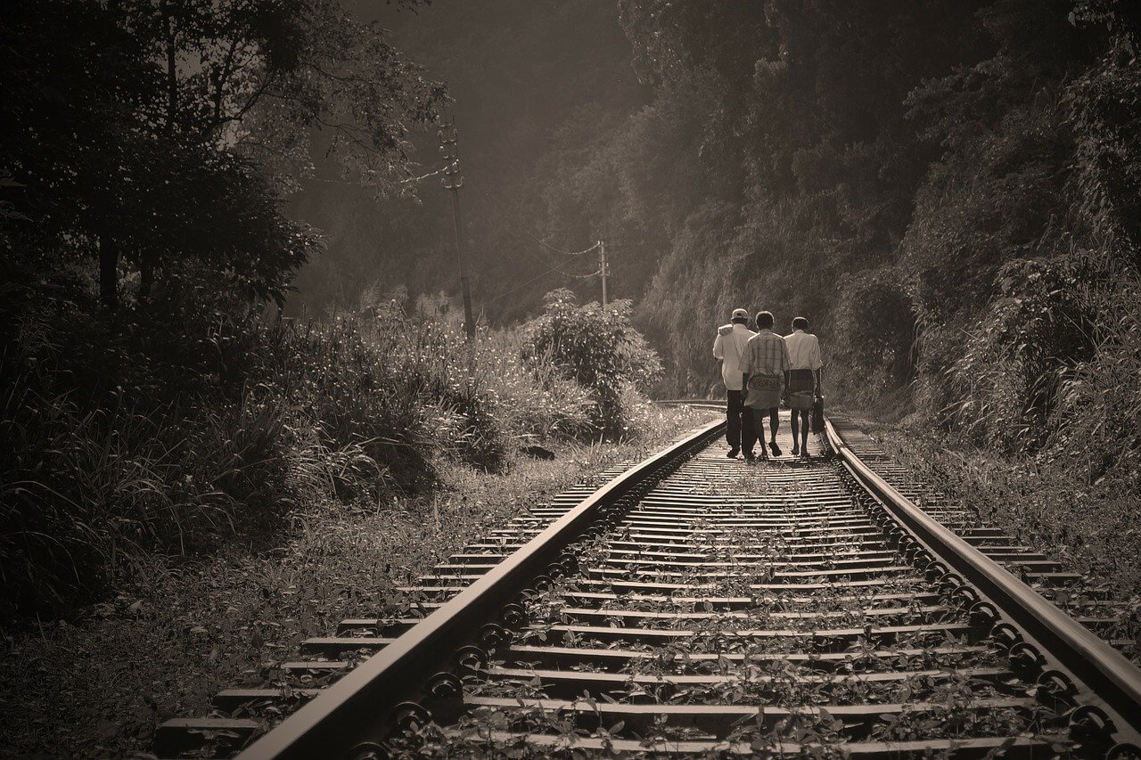 Three men in Sri Lanka walk the train tracks in the hill country