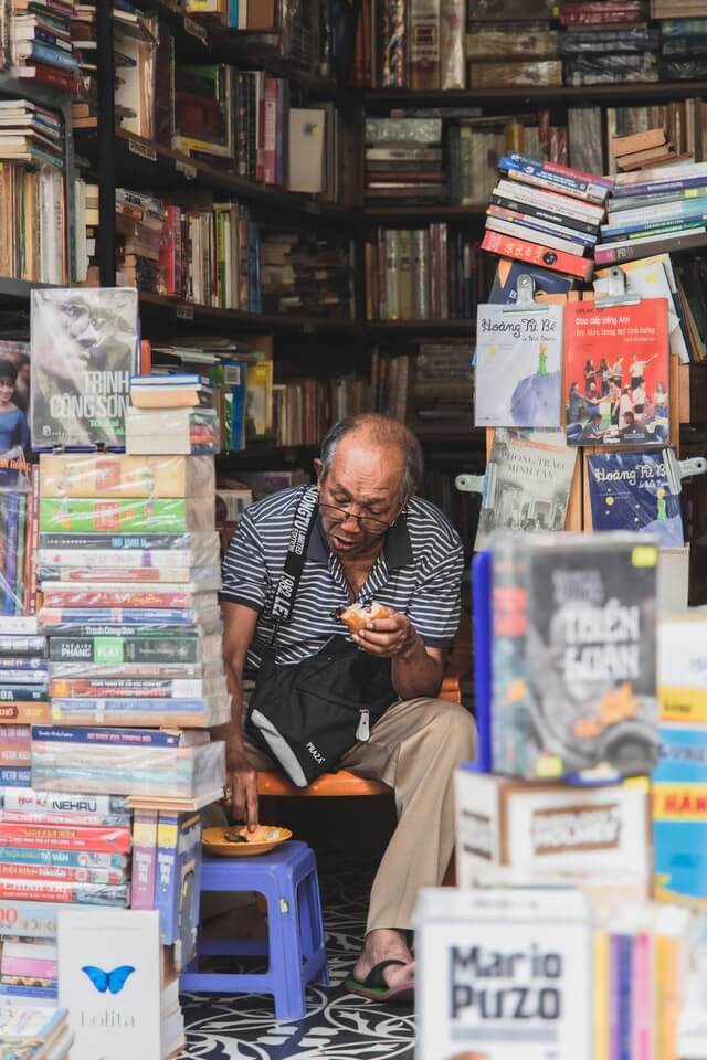 A man sits surrounded by books.