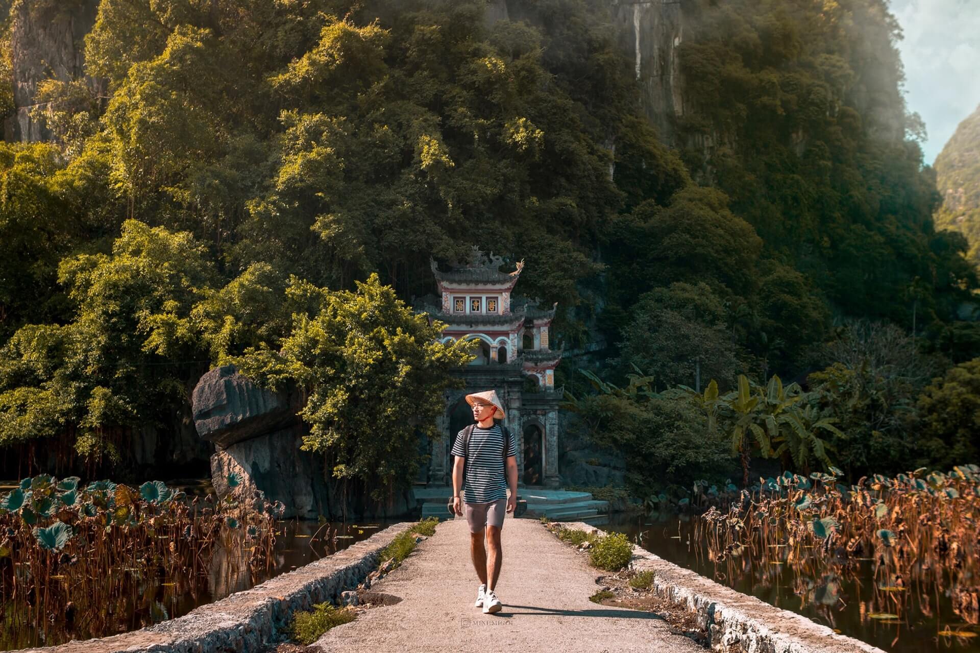 A backpacker in Vietnam crosses a bridge in front of a famous temple