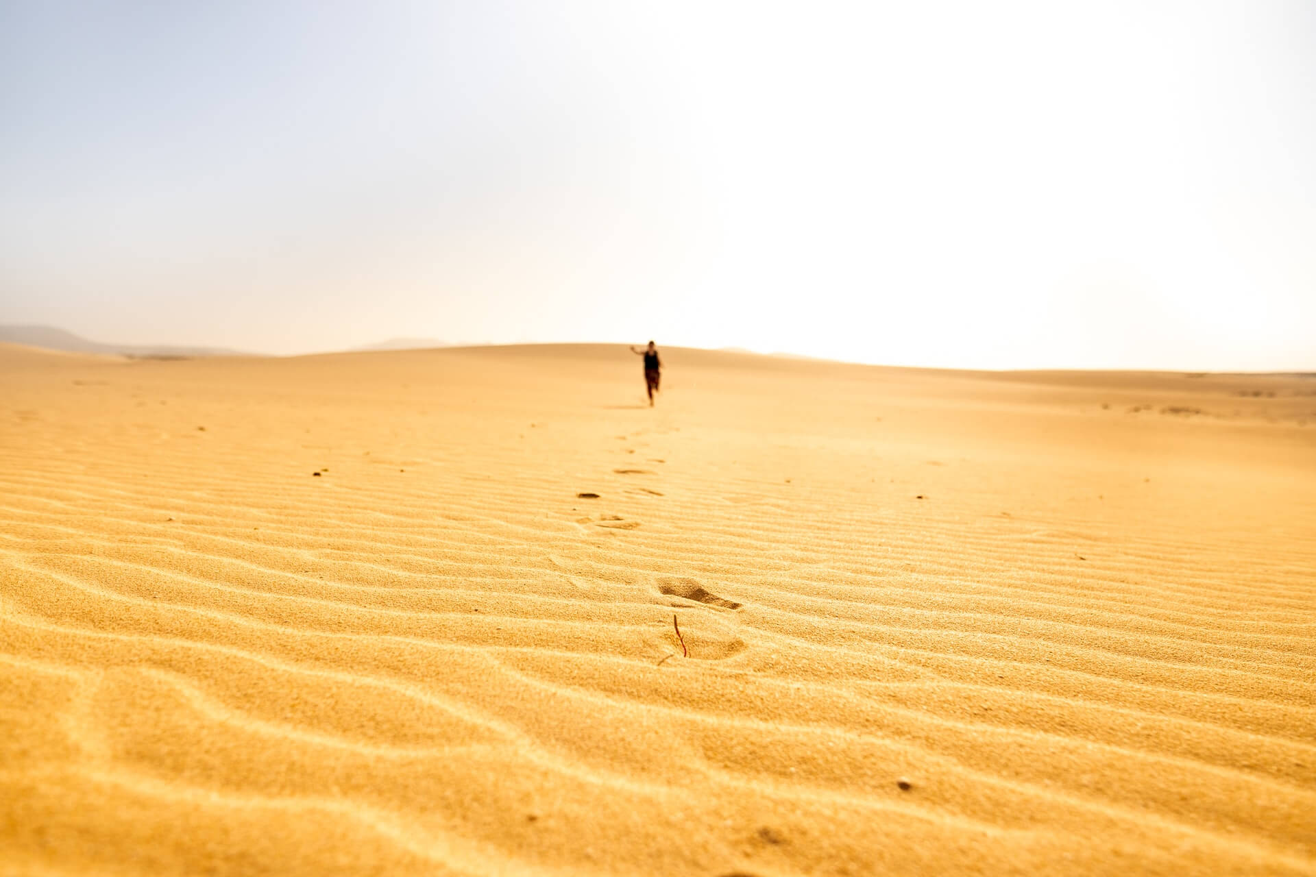 Woman running across sand dunes in the tropical Canary Islands