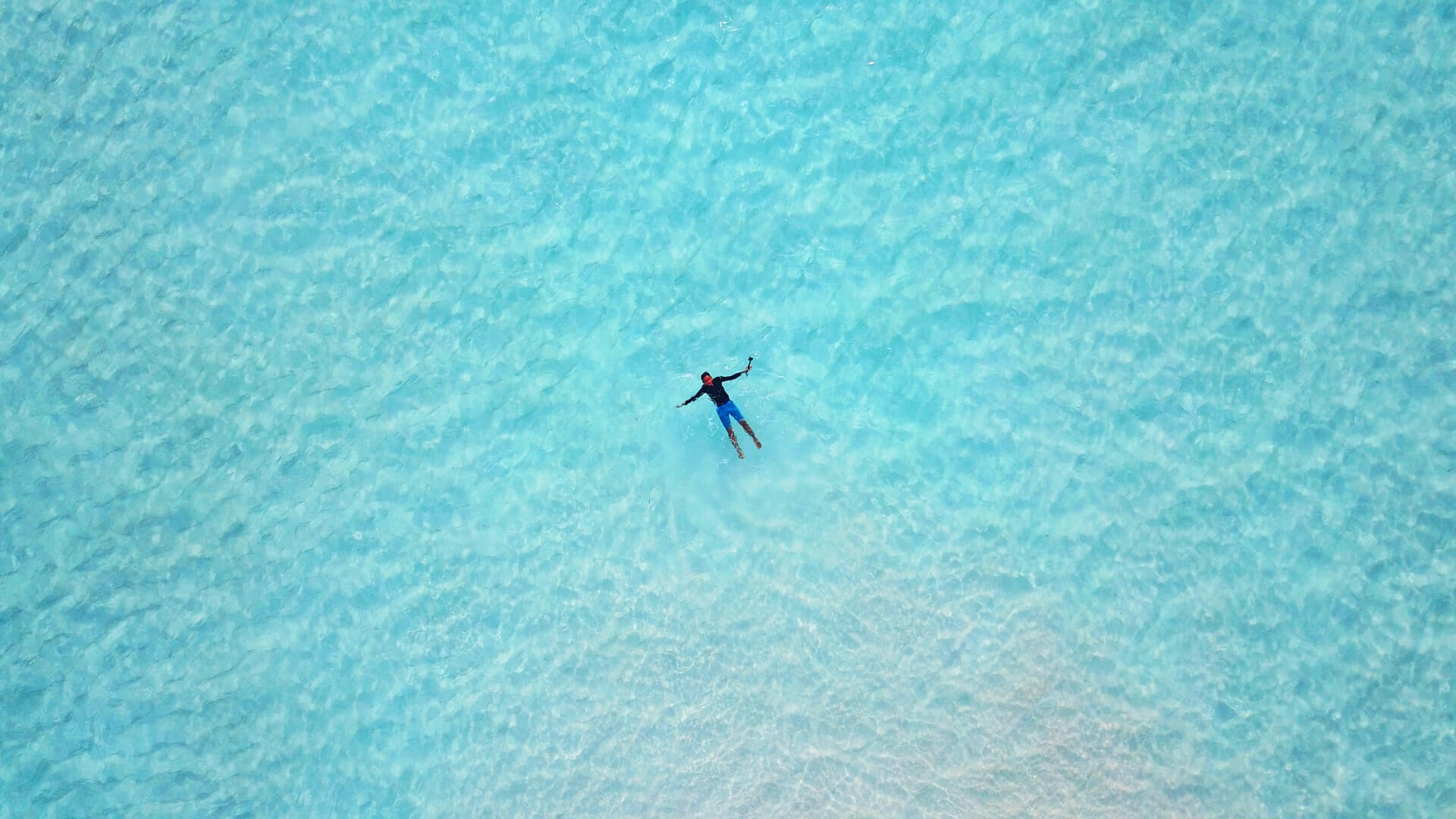 Man floating in the aquamarine waters of Raja Ampa - best tropical vacation spot in Indonesia