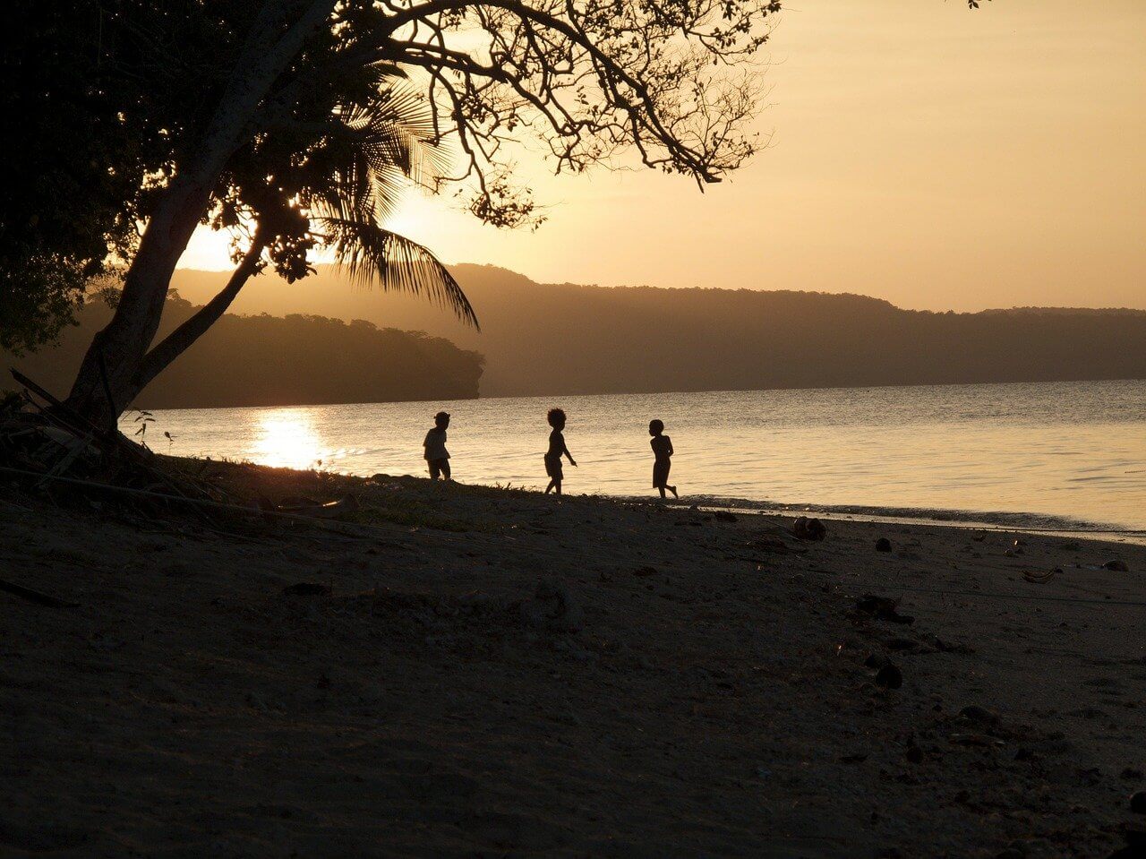 Young boys play on a sunset beach during a tropical holiday in Vanuatu