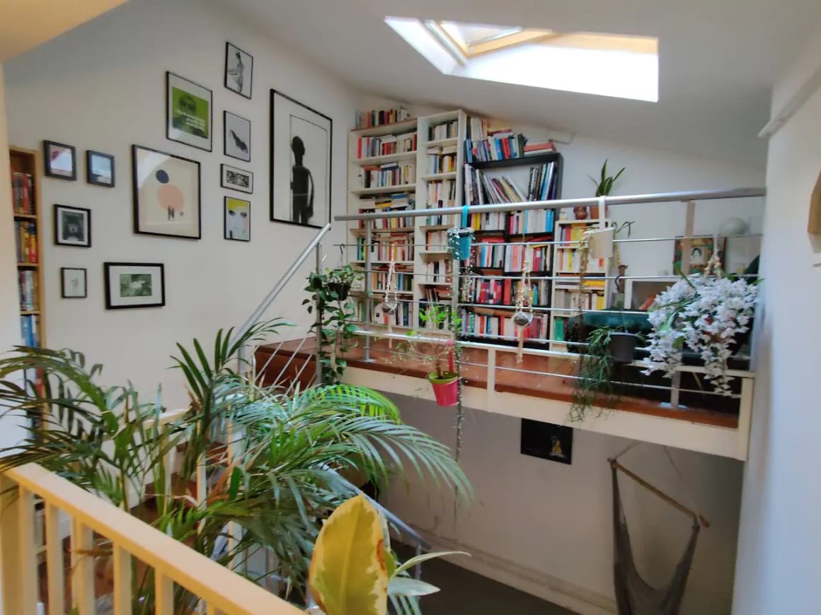 Loft with stairs, book shelf, art and a hammock on the bottom level