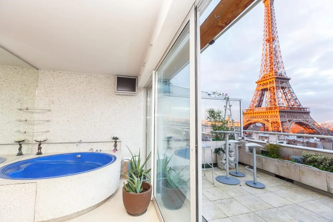 View of bathtub inside, terrace with high table and chairs and an amazing view of the Eiffel Tower.