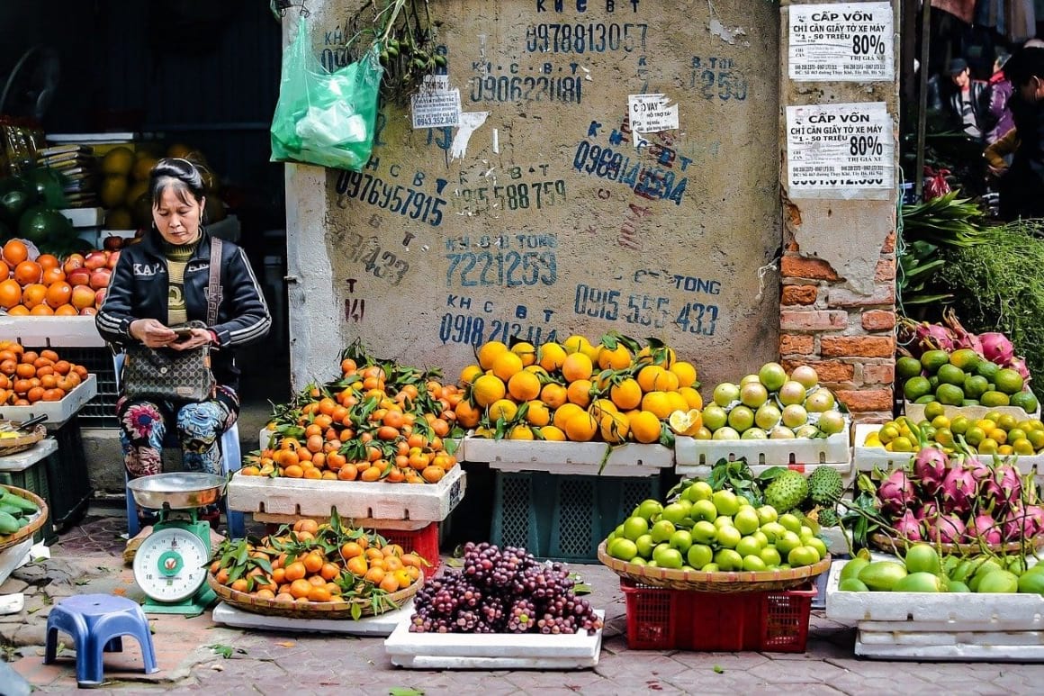 women selling a variety of fresh fruit and veggies in vietnam on the street