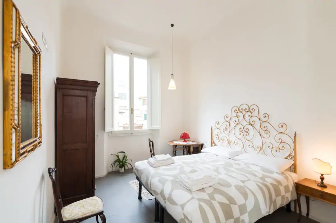 Simple, cosy bed room with a window and a stylish headboard