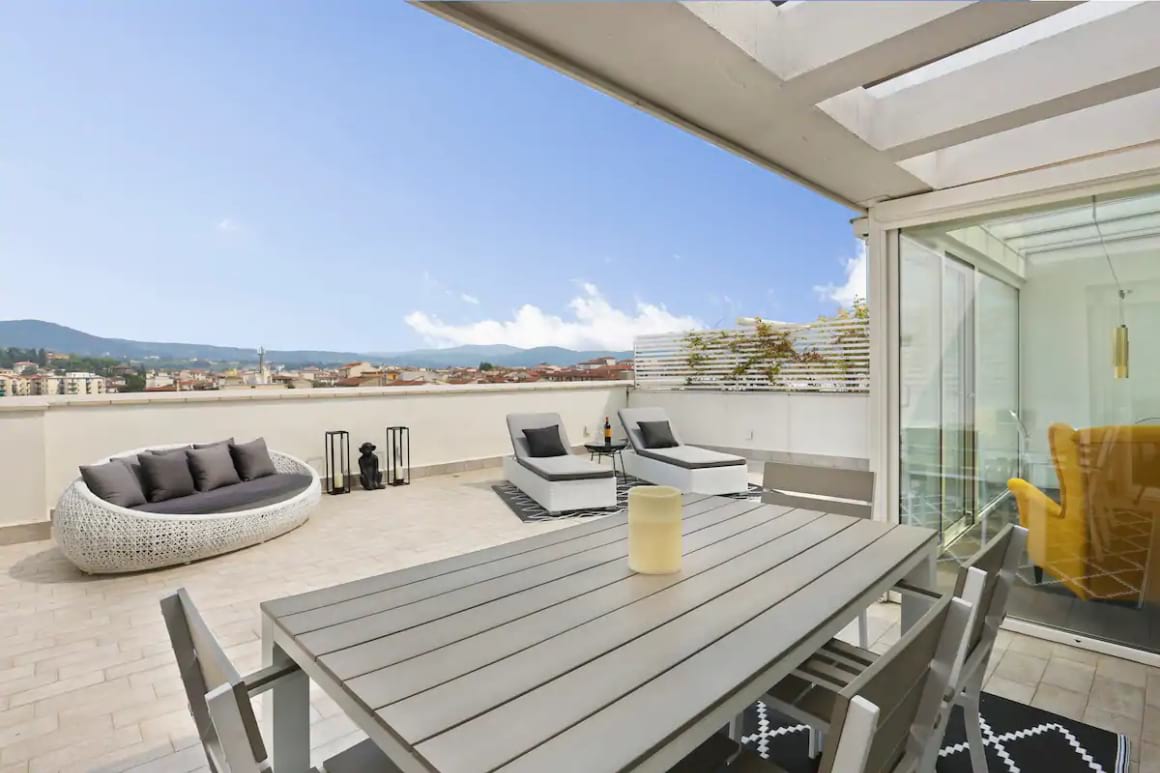 The large, private terrace in the Airbnb with amazing views over the city in background. Dining table and loungers on terrace