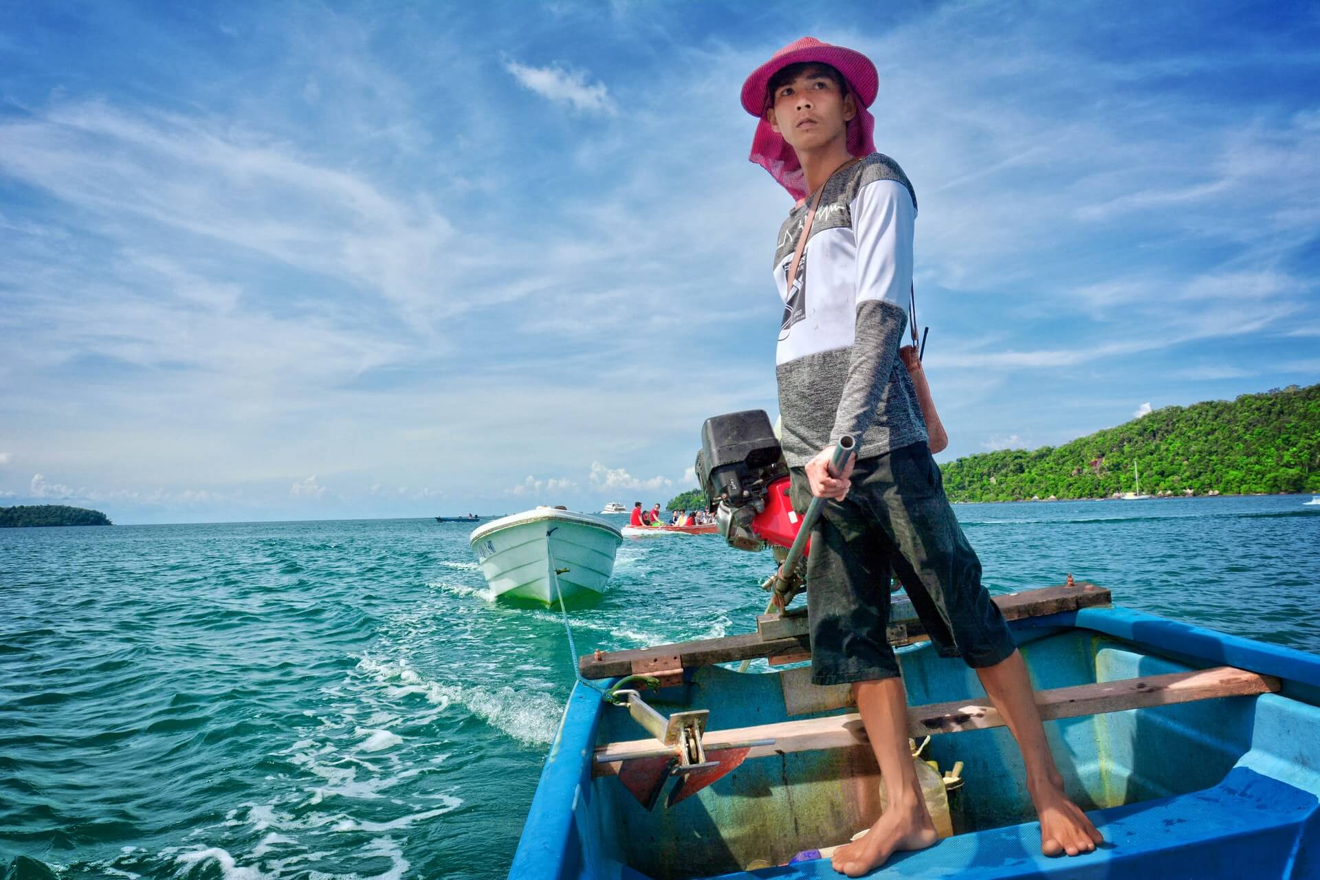 a boy in cambodia standing on a blue wooden boat near koh rong island