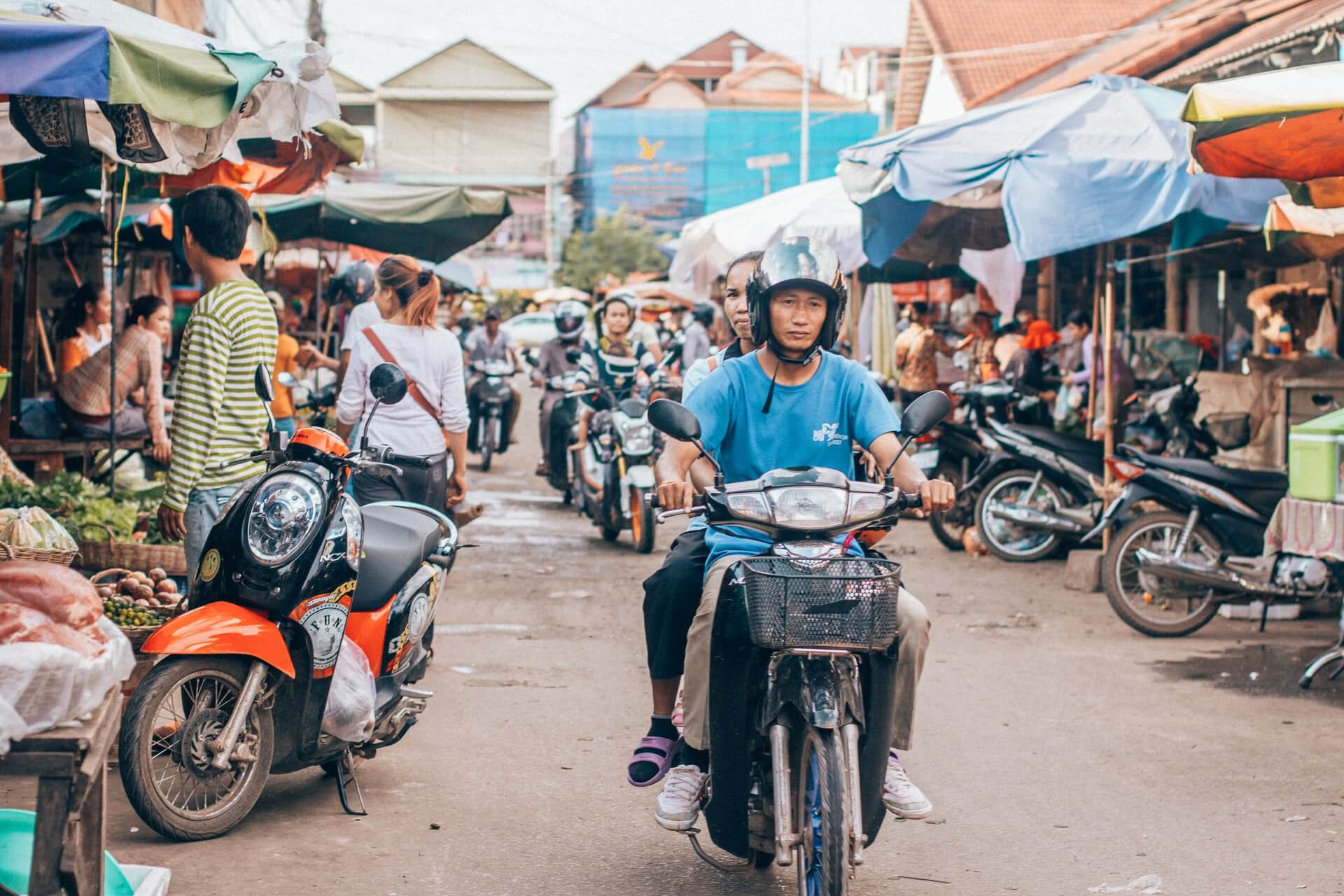 A man in cambodia travelling by motorbike ythrough a city