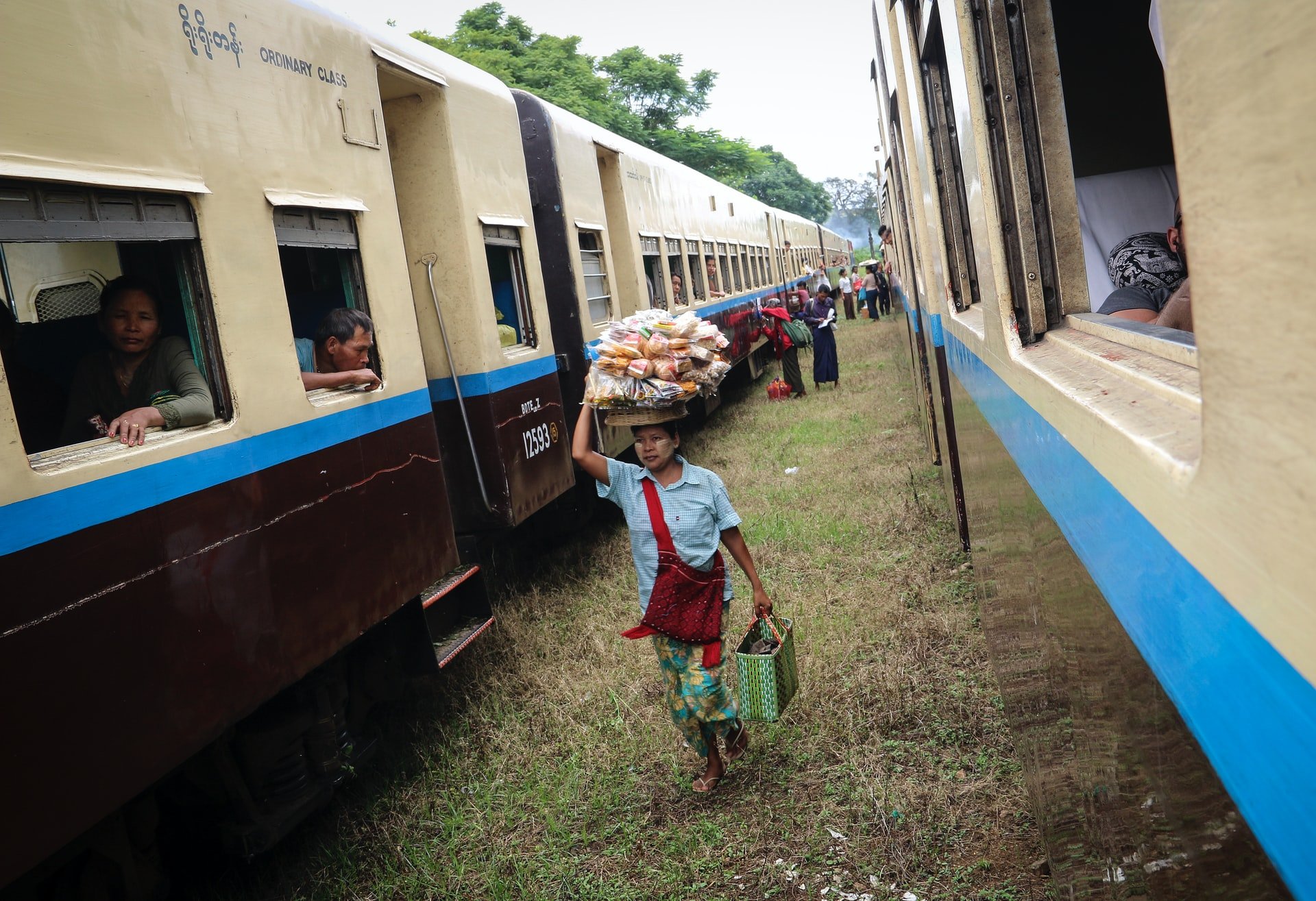 A snack lady selling street food to passengers on a train in Myanmar