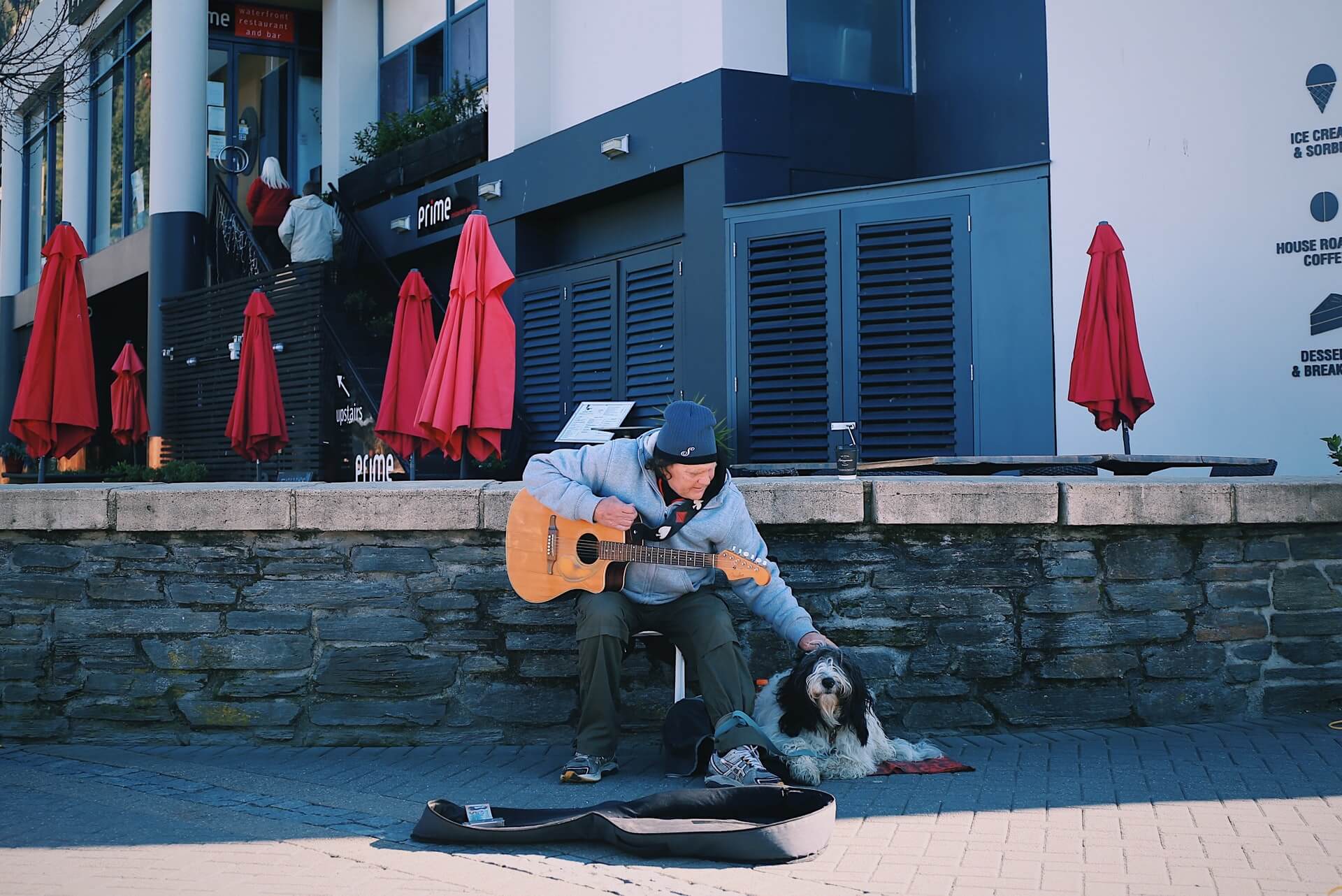 A busker in Queenstown, New Zealand, with his furry companion