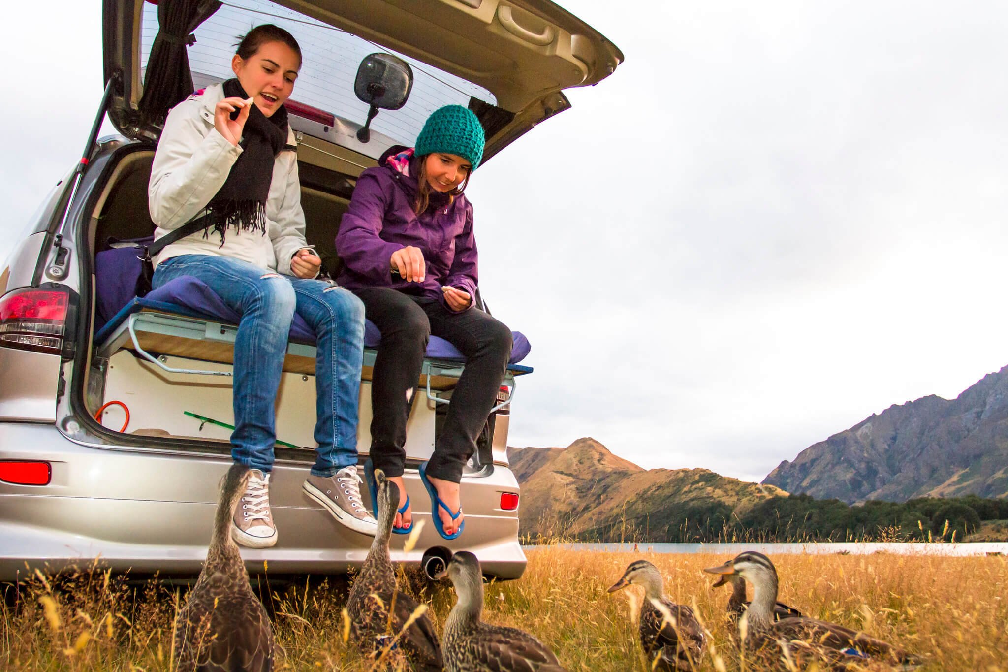 Two girls camping at Moke Lake near Queenstown feed the ducks