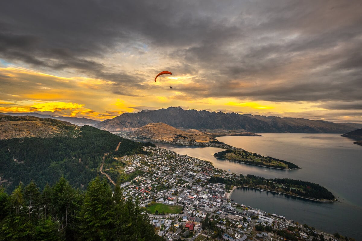 A backpacker paragliding in Queenstown during sunset