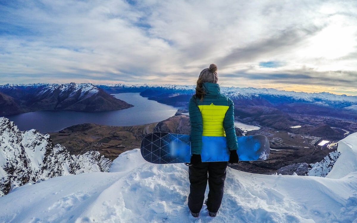 A snowboarder in Queenstown at a lookout in the Remarkables overlooking Lake Wakatipu