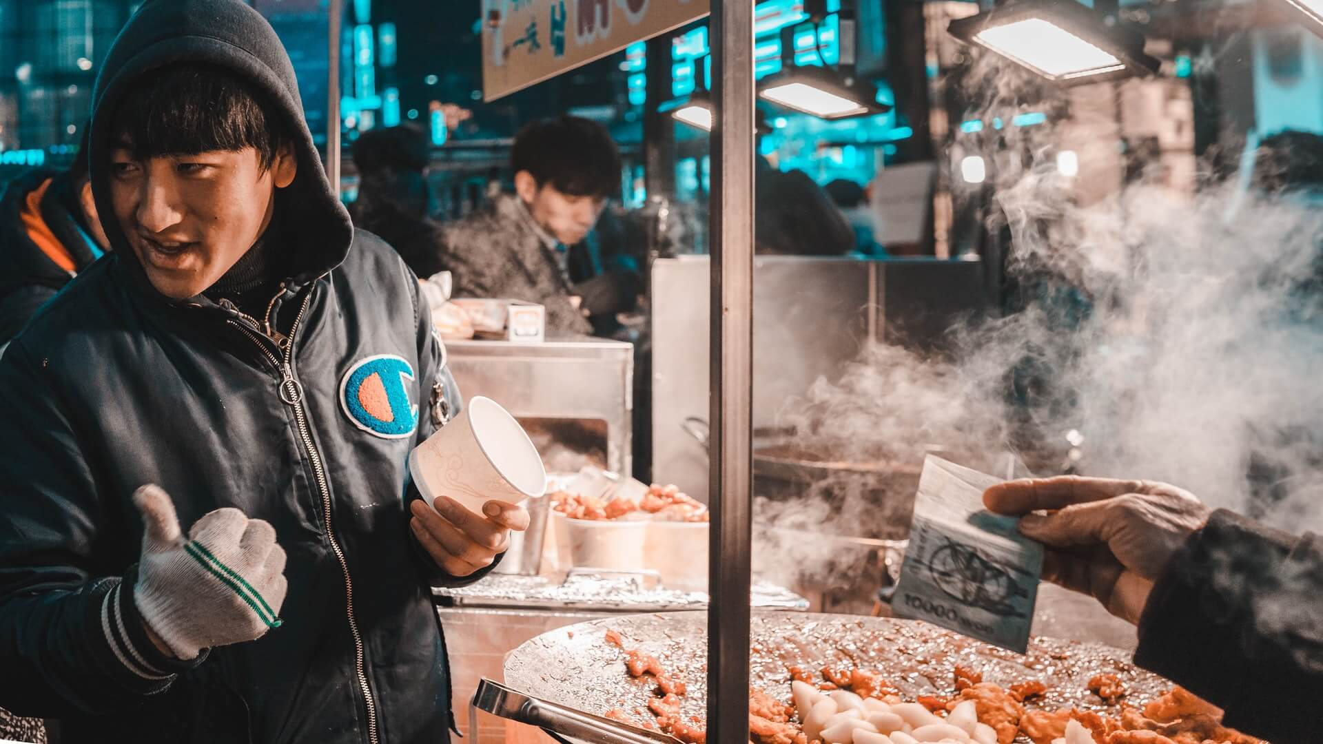 A man stands at a food cart in Vietnam. 