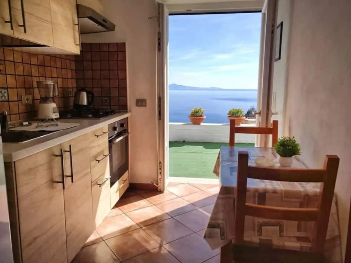 View of the small kitchen area and out the doors to the view of the sea outside over terrace