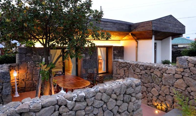 Private Cottage Jeju Island with a stone wall and lights on outside loking welcoming o