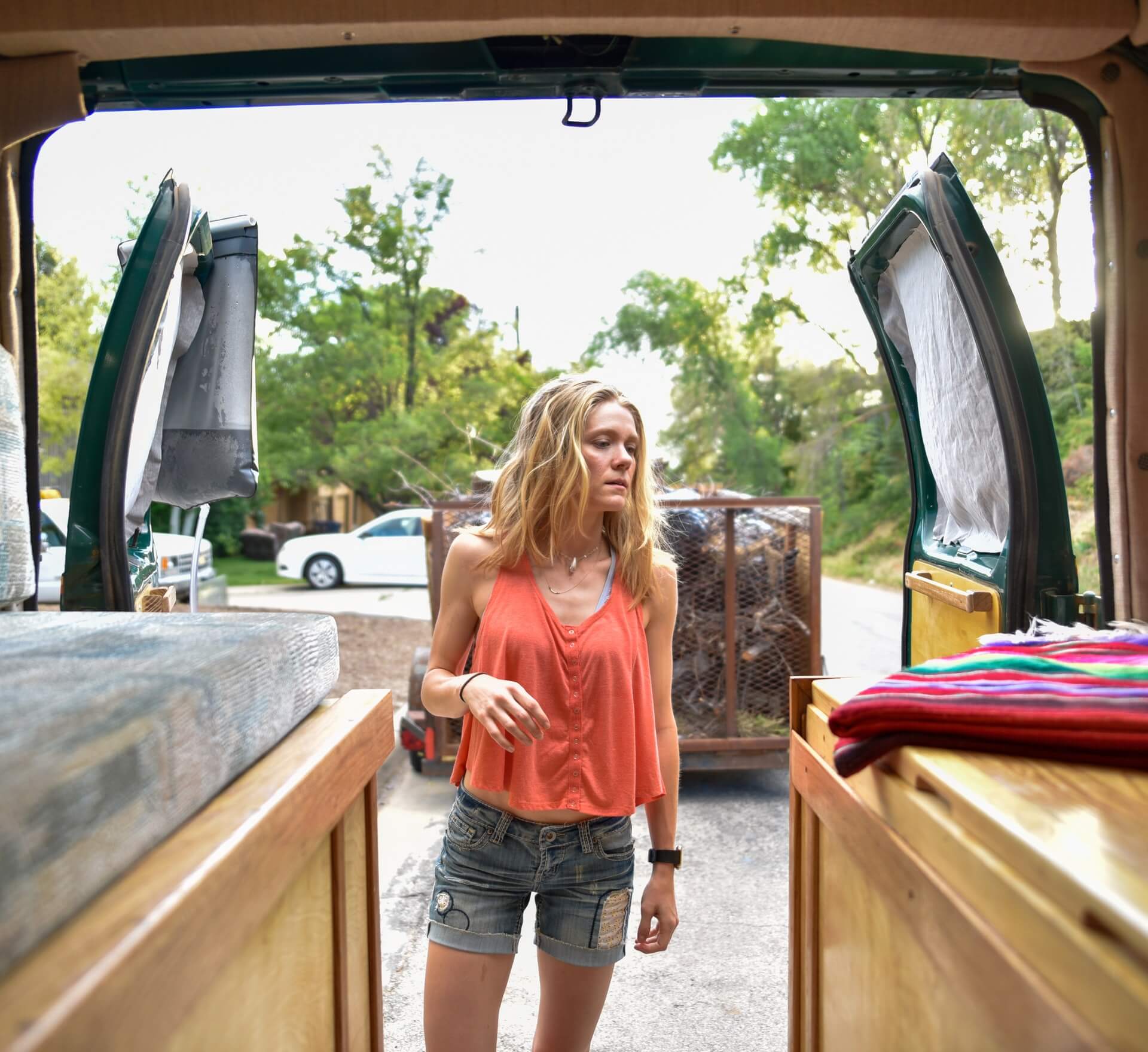 A woman contemplates her RV packing list while organising from the back doors