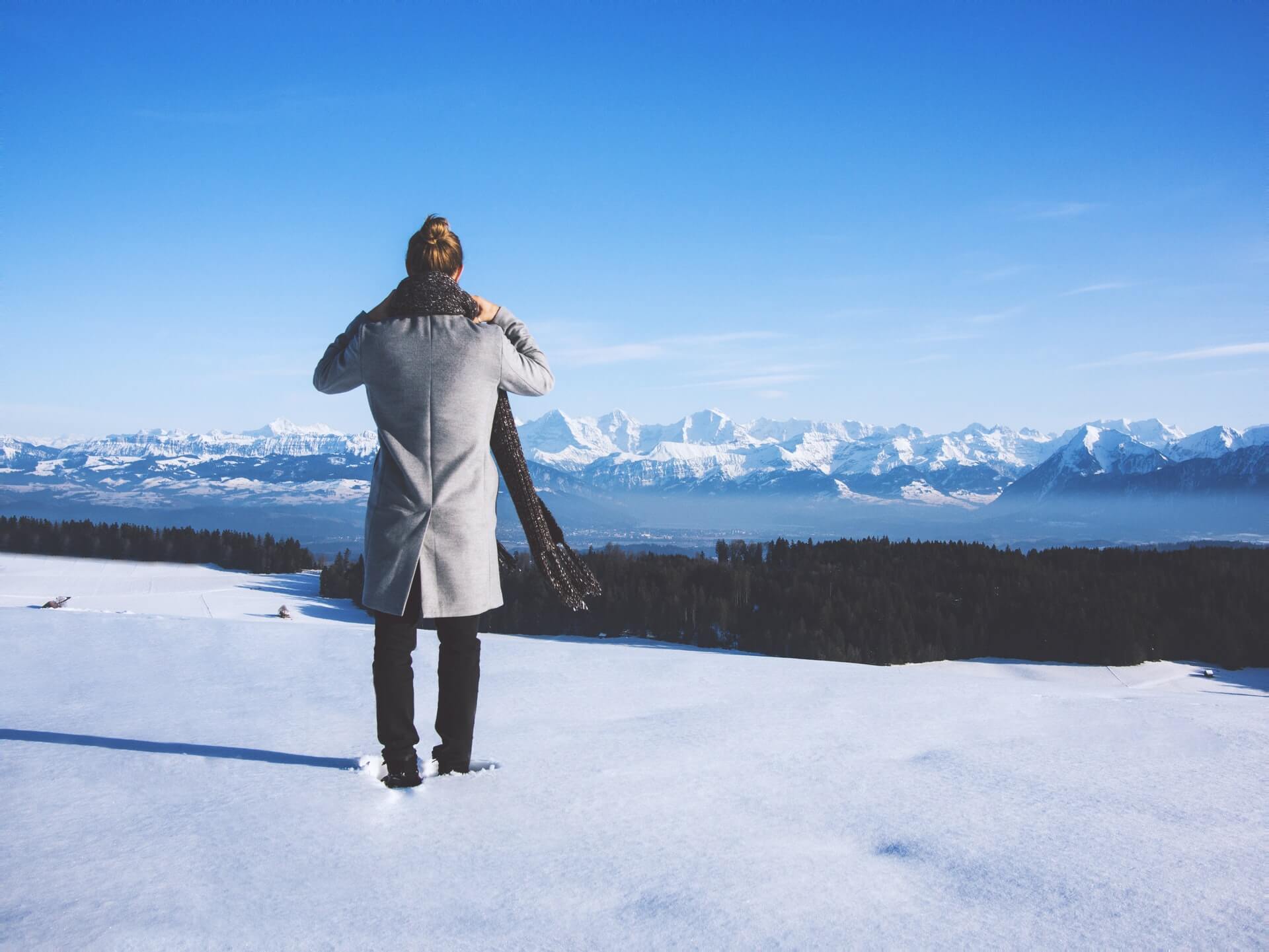 A man on an RV trip wearing his winter packing layers on a snowy cliff