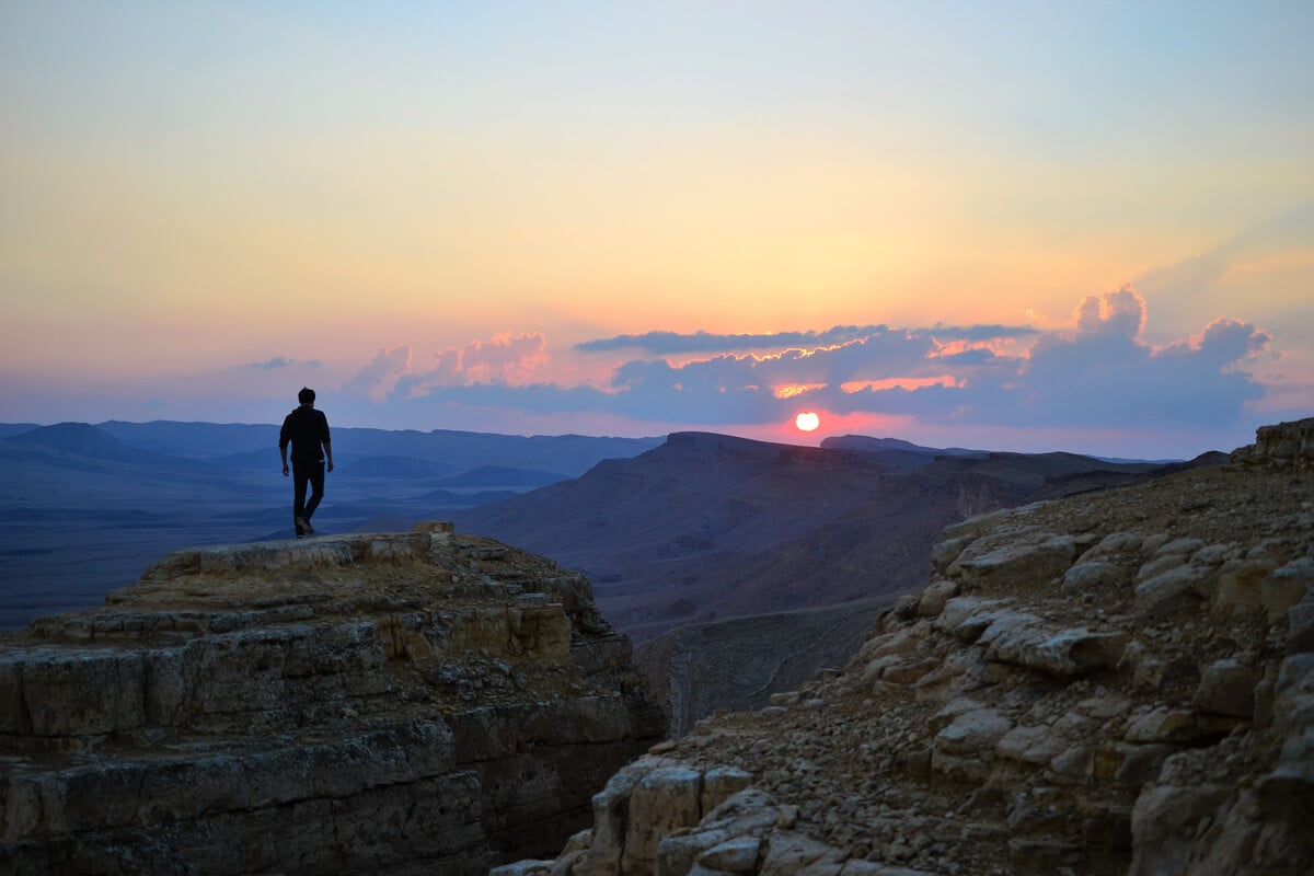 A backpacker in Mitzpe Ramon watches the sunset - best hippy place in Israel