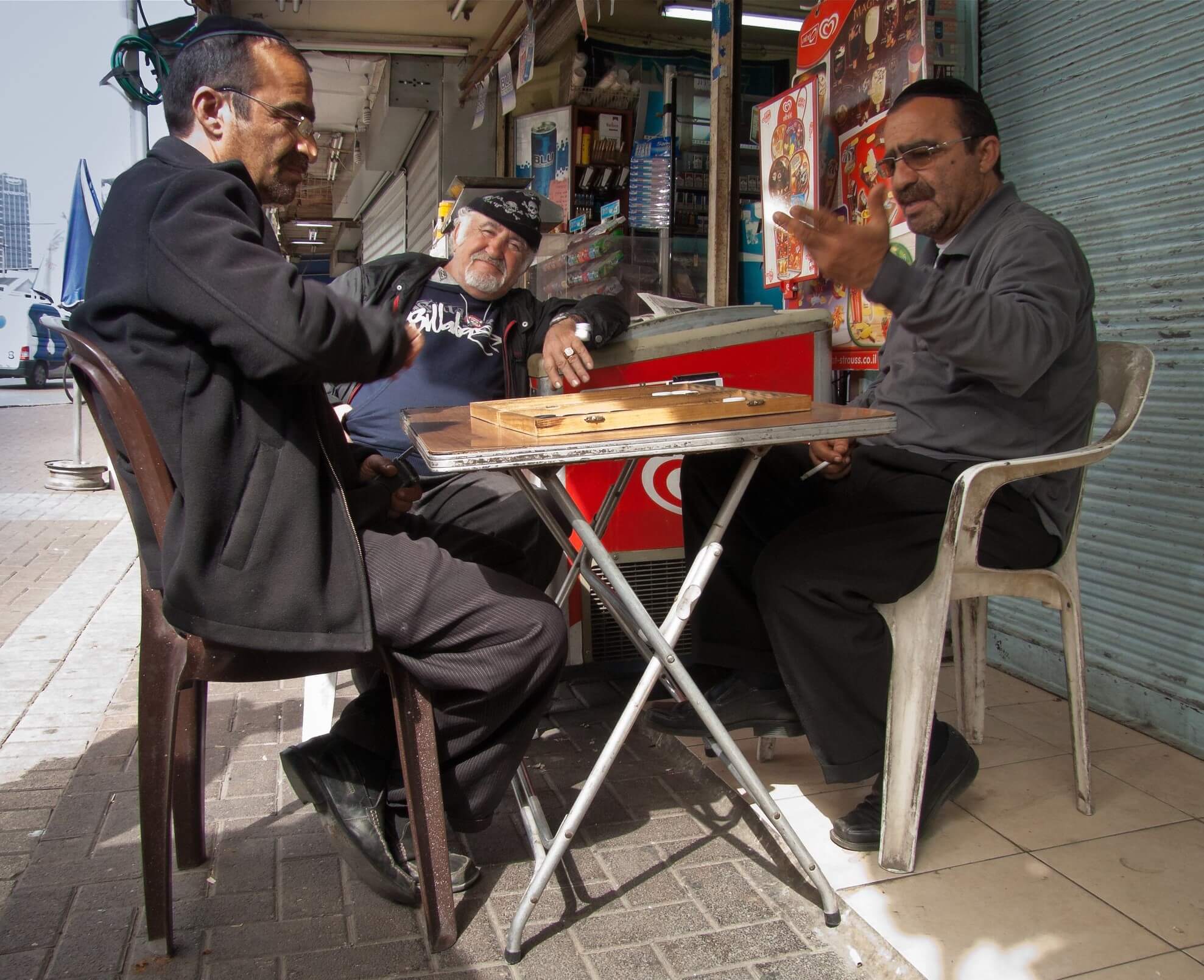 Three men playing shesh besh at a cafe in Tel Aviv - fun things to do in Israel