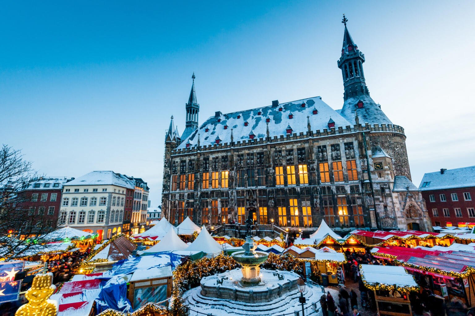snow covering the tops of the buildings and tents at the Aachen Christmas market