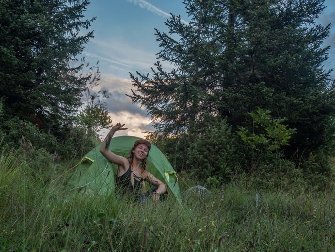 a solo female backpacker in a tent in a forest