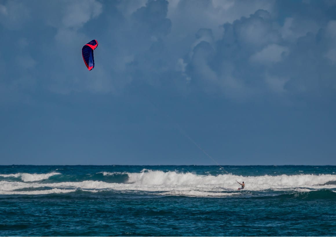 a person kit surfing blue waves on a sunny blue sky day in the dominican republic