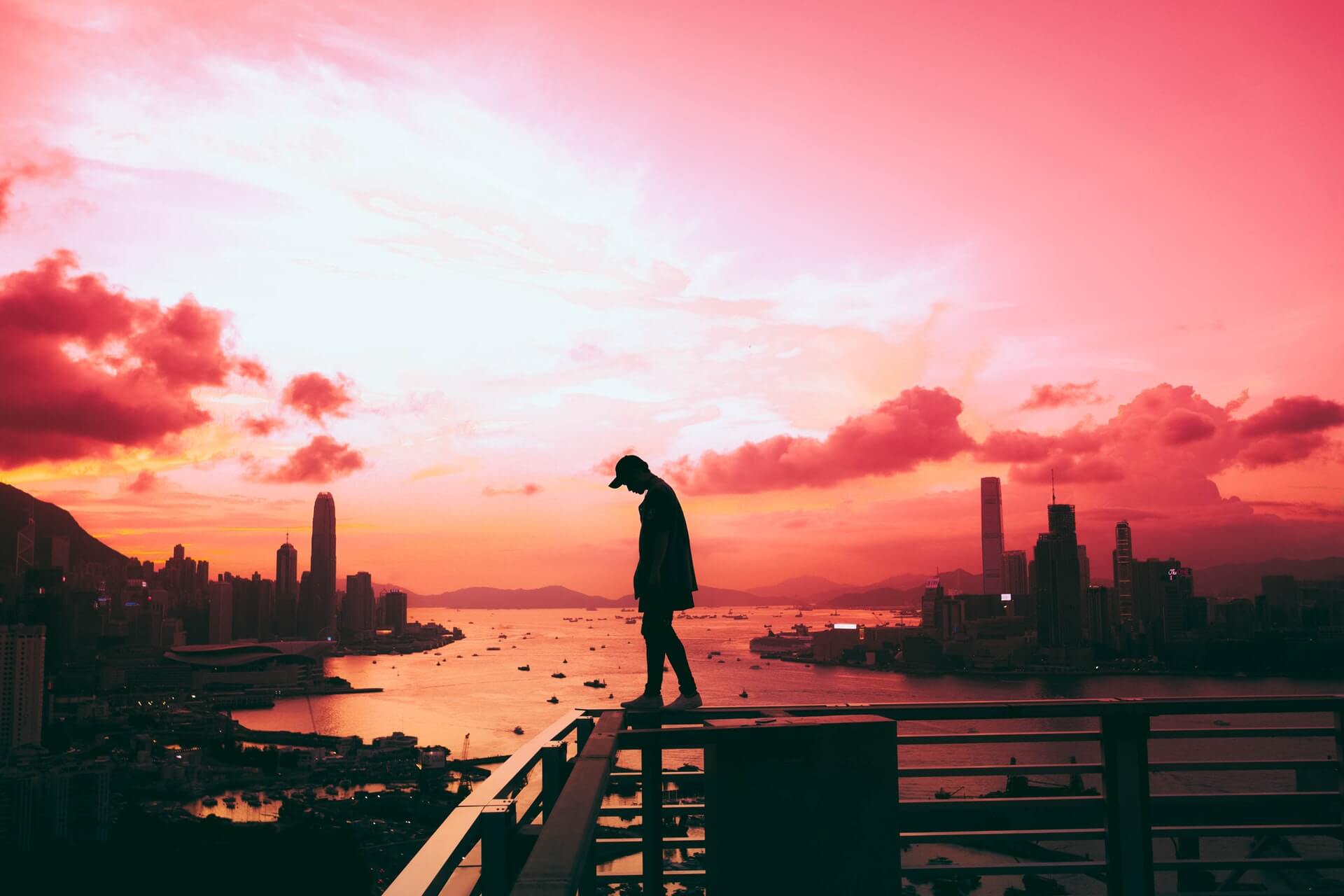 A man silhouetted against a crimson sunset in Hong Kong