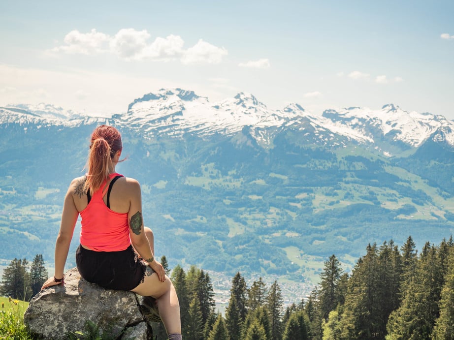girl in a pink top with travel tattoos looking at mountains