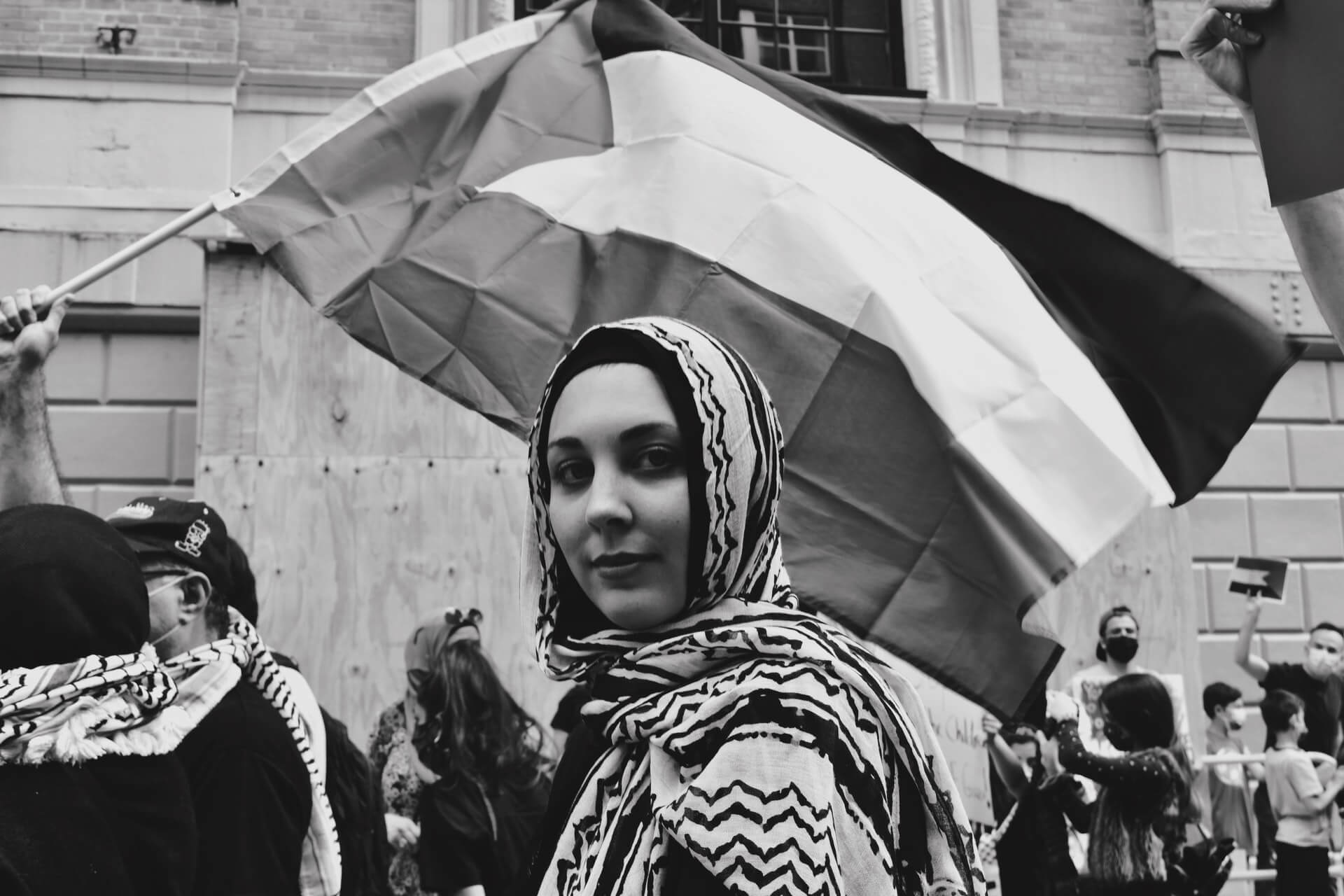 A Palestinian woman with a flag behind her at a protest in Palestine