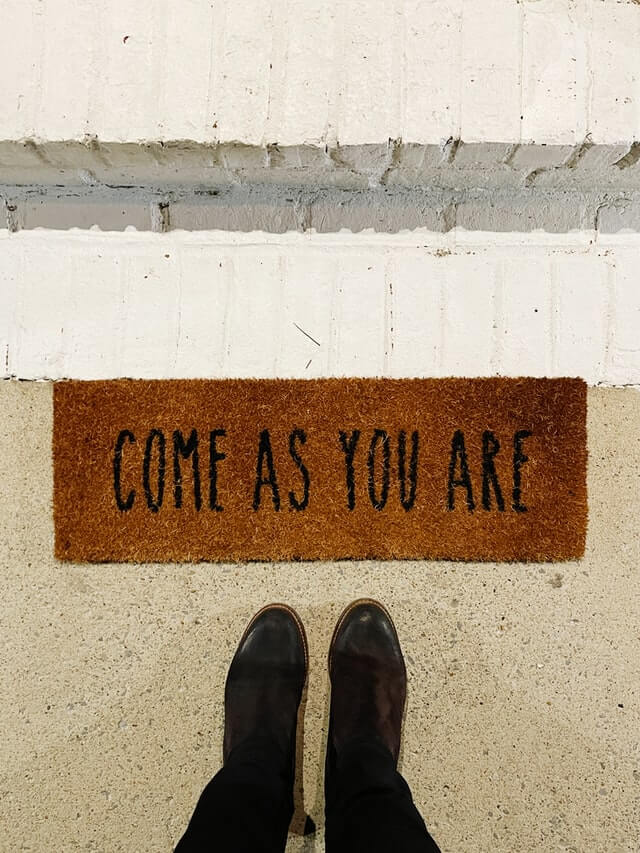 A doormat with the phrase 'Come as You Are' defining hostels in a sentence