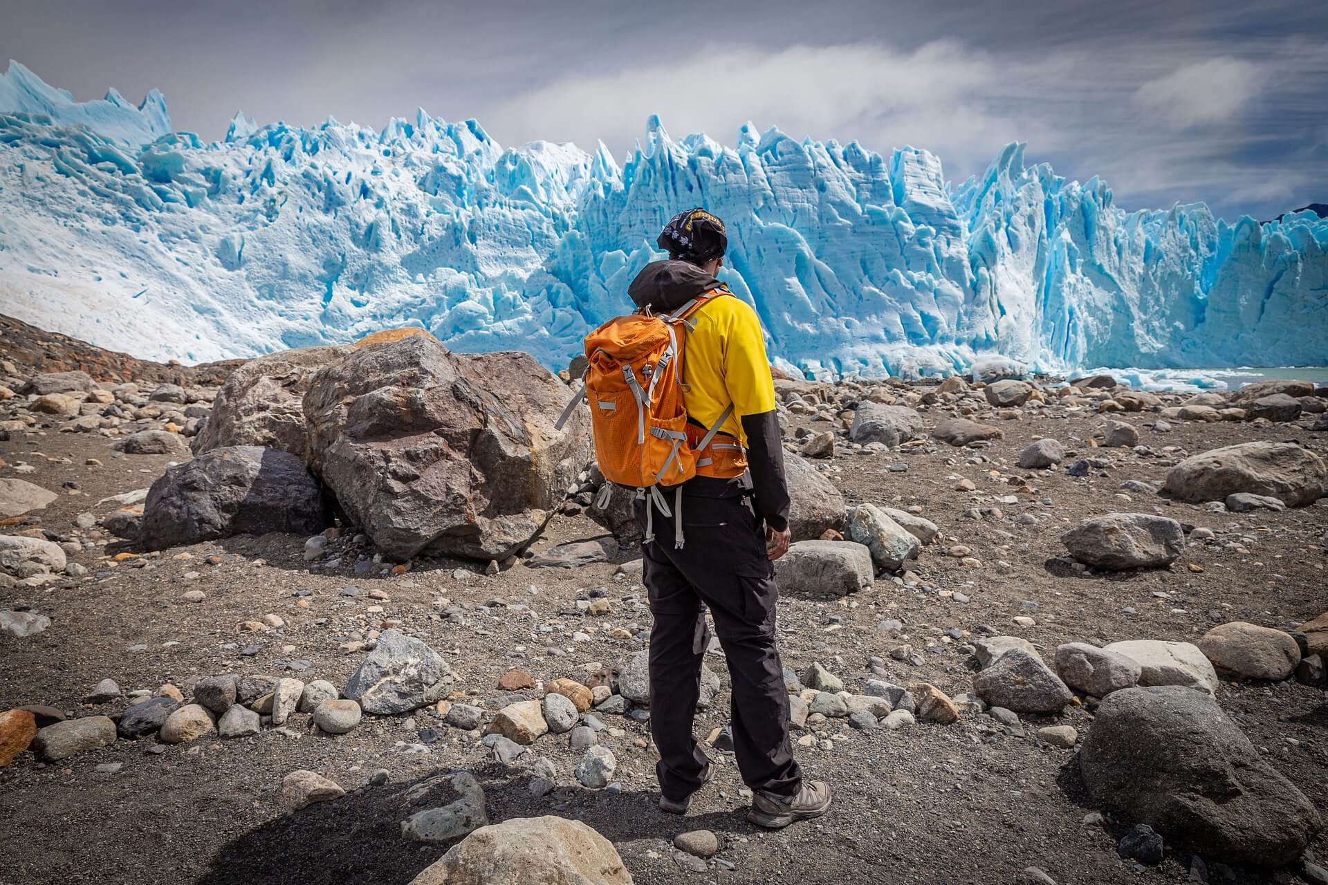 hiker looking at a blue-white glacier in 