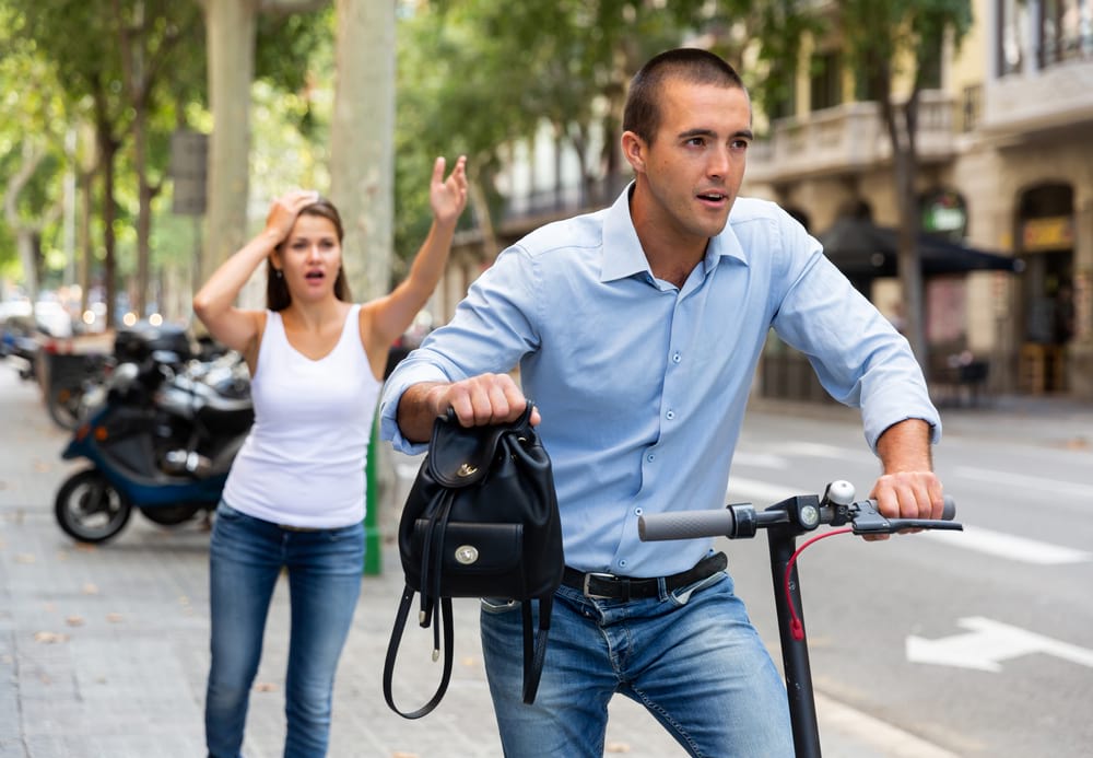 man on electric scooter robbing blonde womanpickpocketing scam