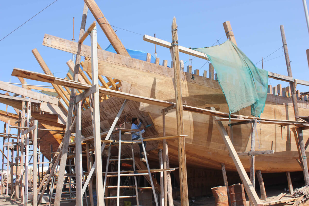 a man works on a traditional dhow boat in sur oman