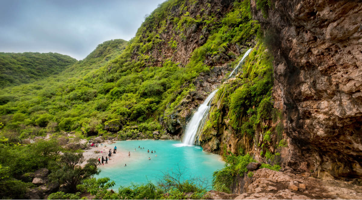 waterfall pouring into a bright blue pool in salalah oman
