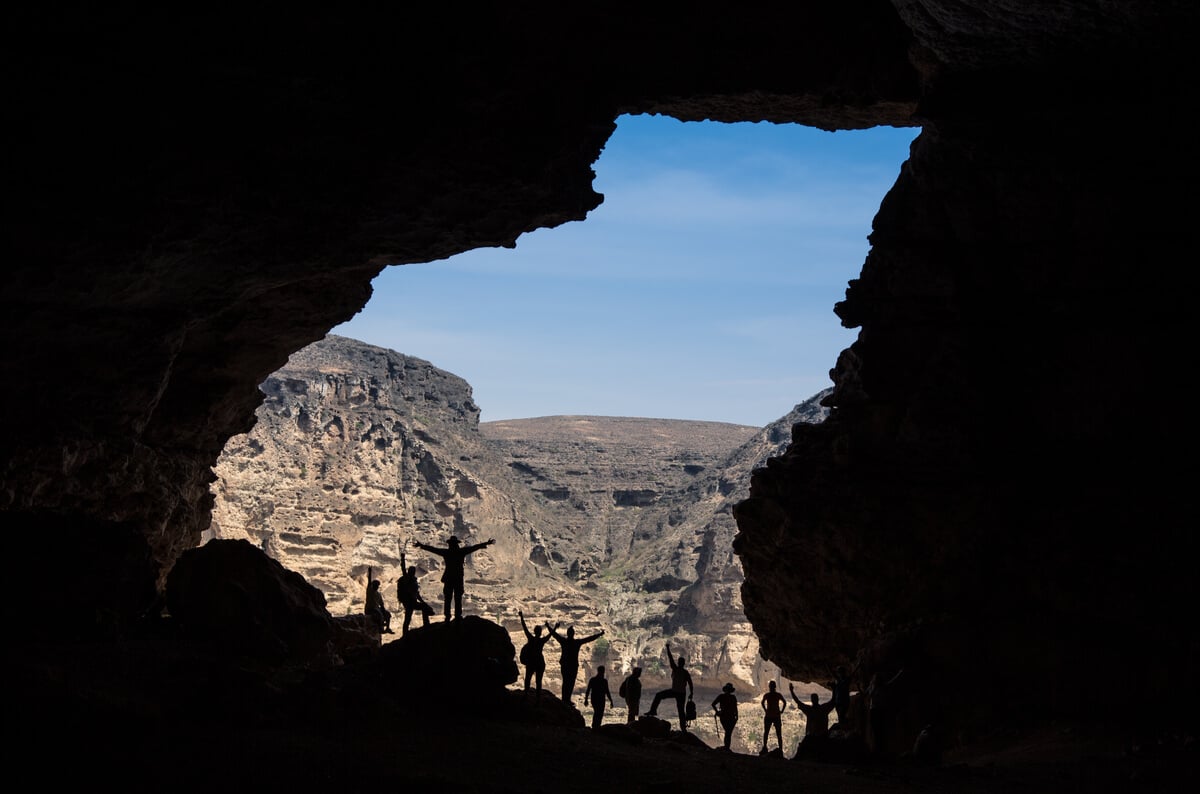 shadows of people standing at one of the openings of the tayq sinkhole a place in oman