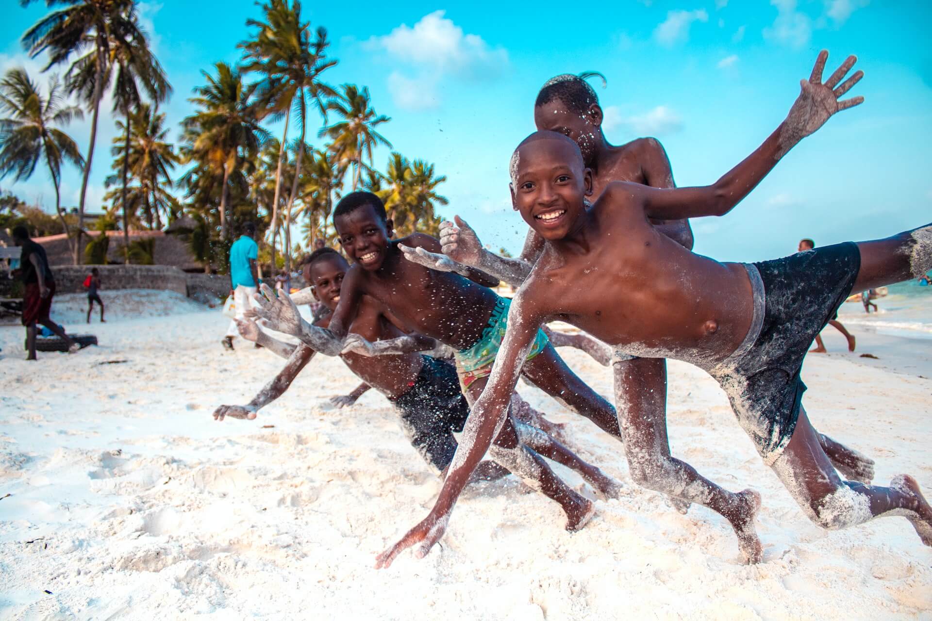 Kids on a beach in Kenya play with a volunteer