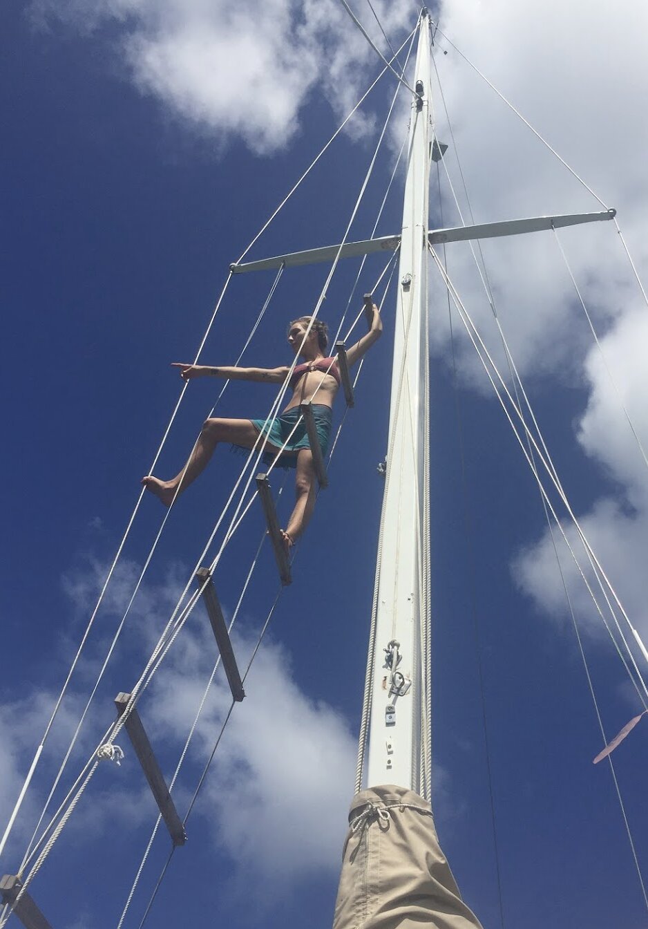 A girl is in the rigging of a sailboat in French Polynesia