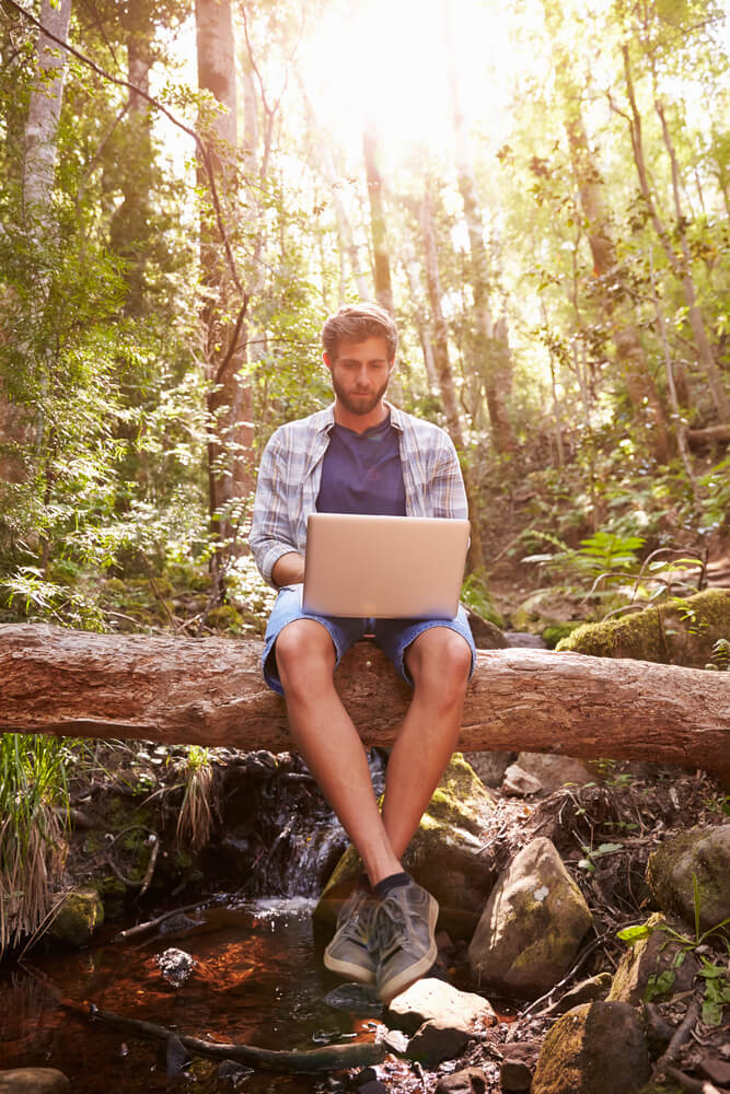 digital nomad working on his laptop in the forest
