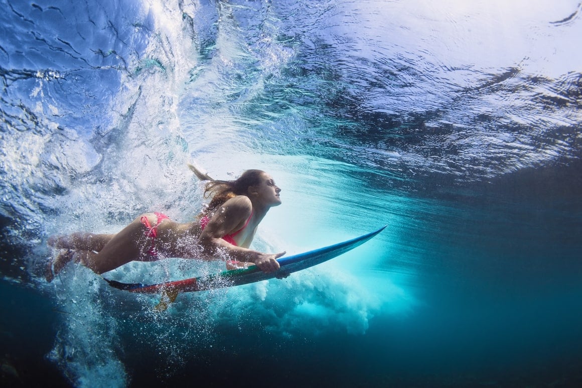 A girl ducks dives under a wave in French Polynesia