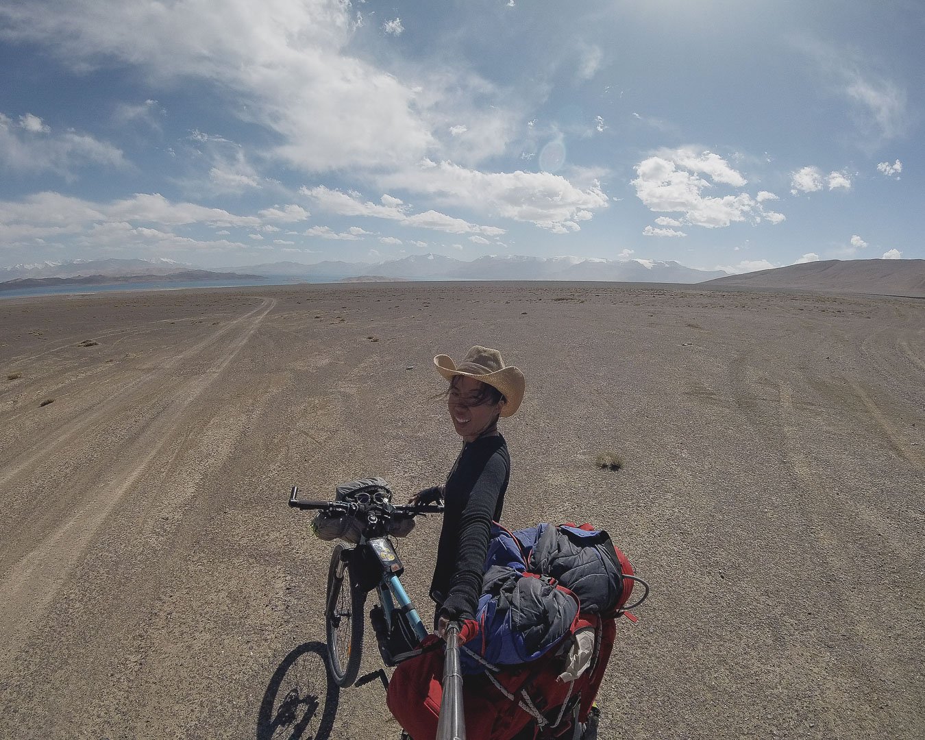 A girl on a bike is in the centre of the frame. She is on a bike with a hat on. 