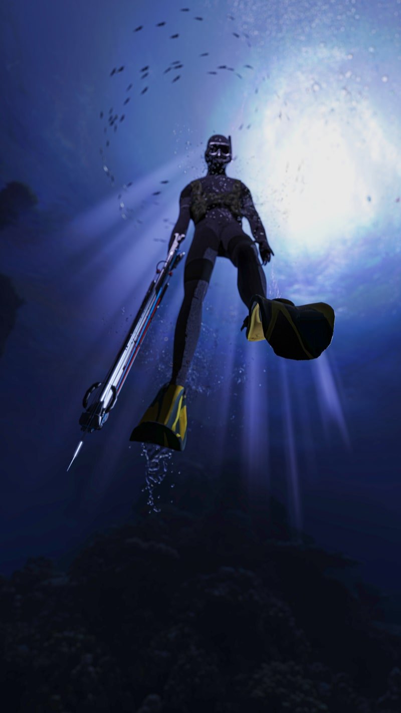 A diver with a speargun in hand swims toward the surface