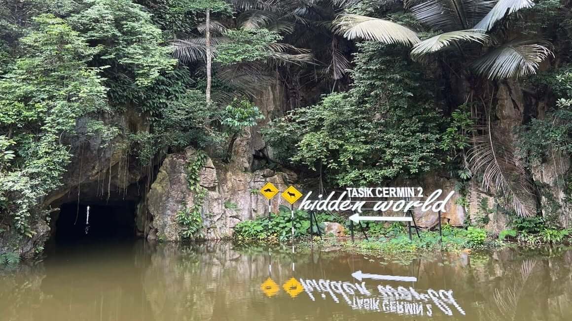 A lake leading to a cave surrounded by greenery in Ipoh, Malaysia