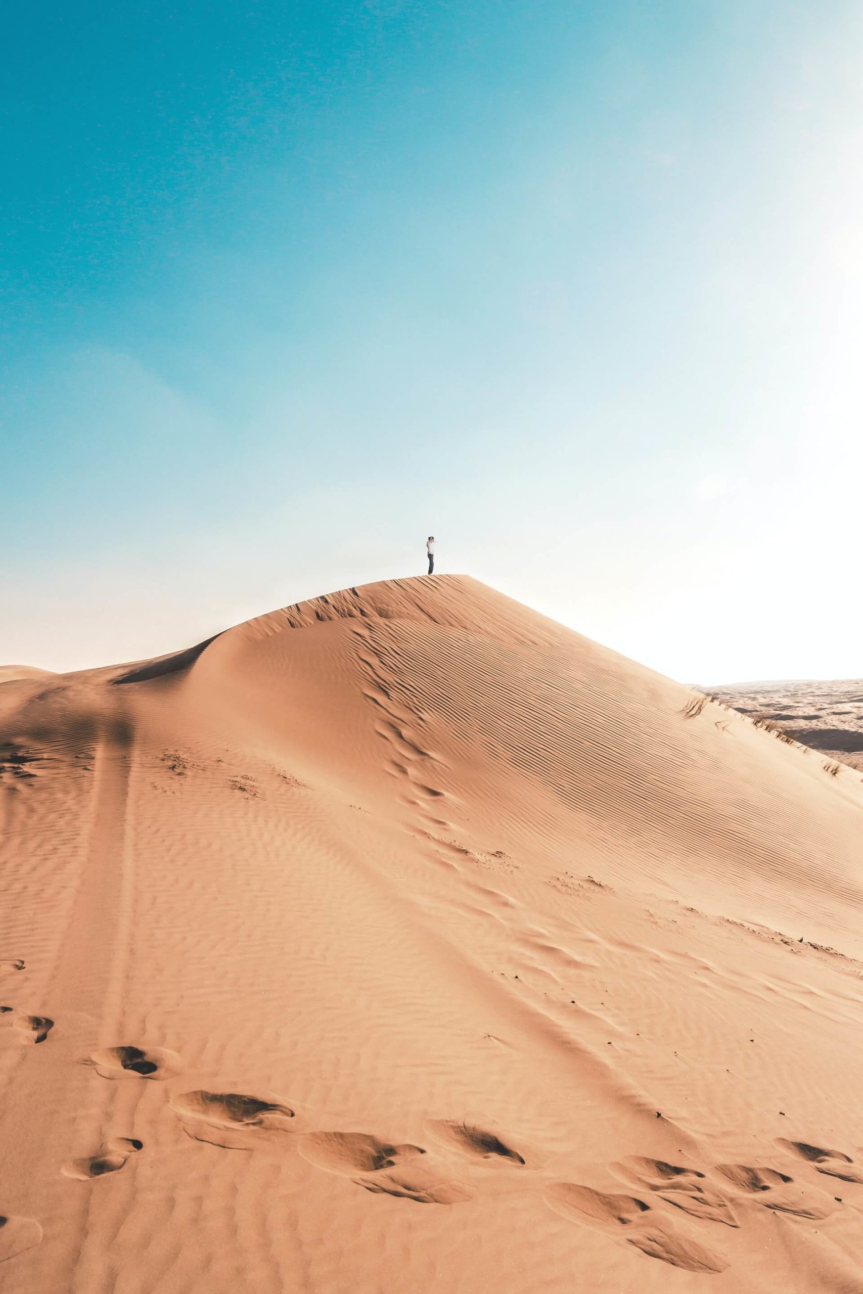 A backpacker in Oman summits a dune in the Sharqiyah Sands