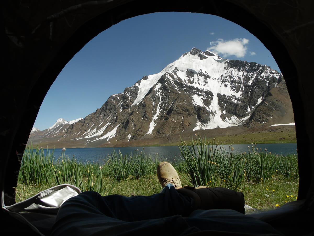 feeet poking out of a tent at karambar lake hiking in pakistan